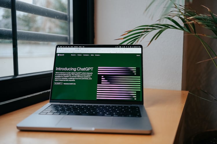 A laptop with a screen featuring OpenAI's ChatGPT landing page
